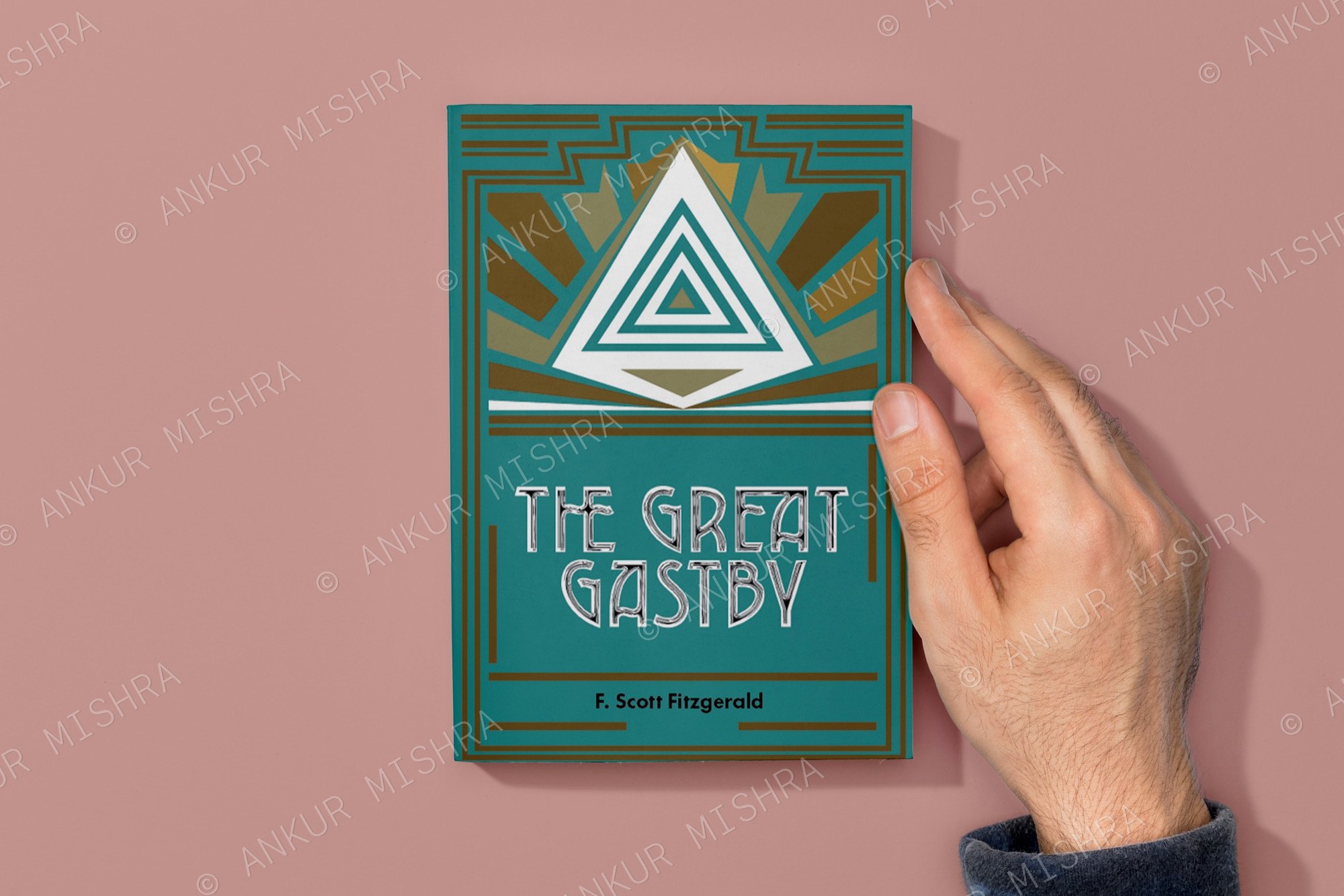 The Great Gatsby redesign held flat on a pink surface