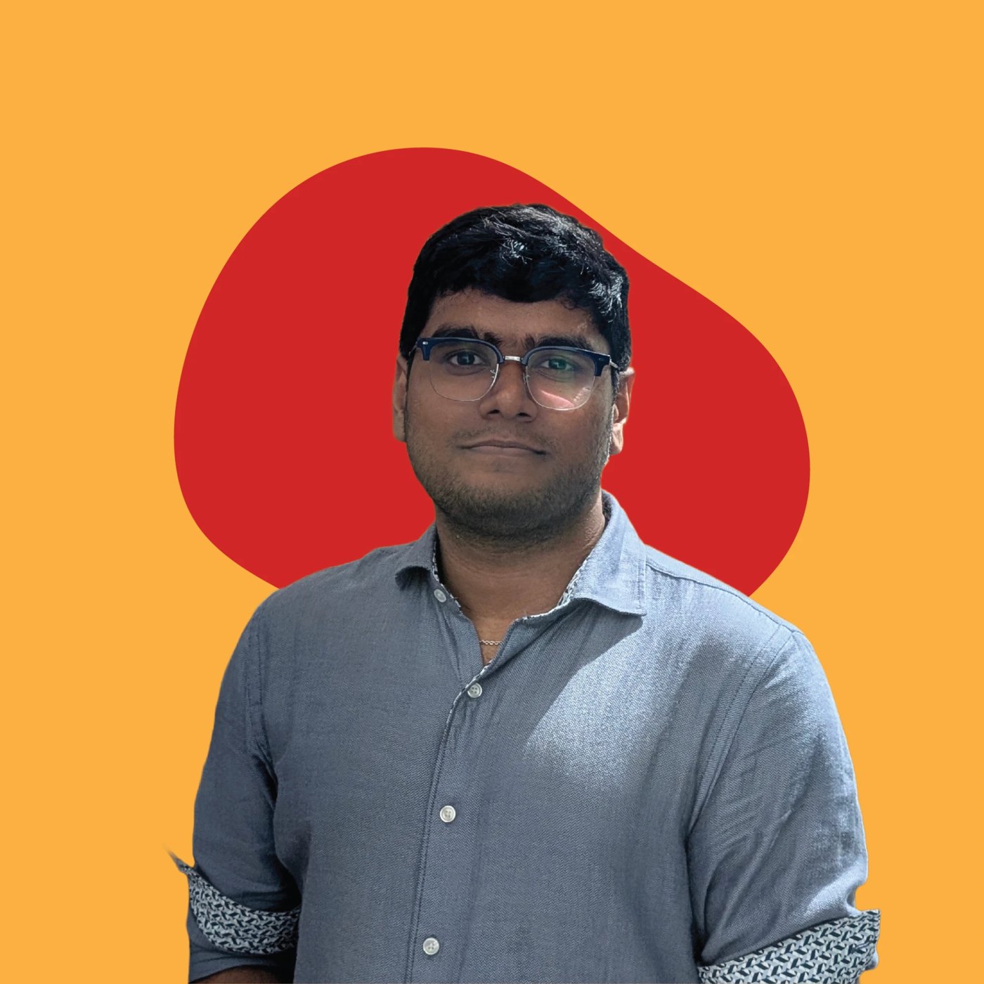 Portrait of Ankur Mishra in glasses and a blue button-up shirt, in front of a red shape